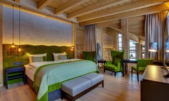 A modern bedroom with a wooden ceiling and elegant furnishings. Decorated in green and neutral tones, it creates a relaxing atmosphere.