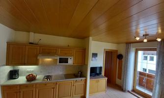 The image description shows a modern kitchen with wooden cabinets and a stone countertop. A window with access to the balcony provides natural light in the room.