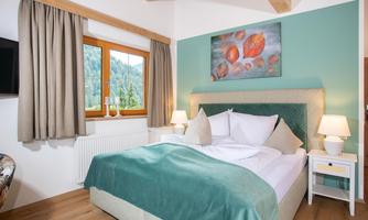 A modern bedroom with a comfortable bed and soft colors. The room has large windows that let in a lot of natural light.