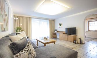 A modern living room with a comfortable sofa and a wooden table. Large windows let in plenty of daylight and create a bright, welcoming atmosphere.