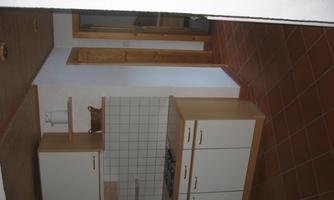 A modern kitchen with white cabinets and a tiled floor. The space is bright and inviting.