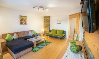 A cozy living environment with a comfortable sofa and a modern television. The walls are painted in light colors and there is a beautiful decoration with plants.
