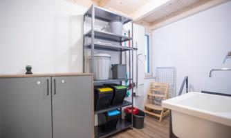 A functional space with shelves that hold storage containers and cleaning supplies. A sink and a space-saving clothesline are also available.