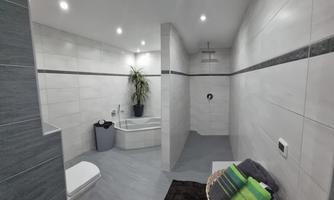 A modern bathroom with bright tiles and a large shower. In the background, there is a bathtub and a plant adds a cozy atmosphere.