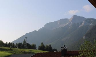 A picturesque mountain panorama with gentle hills and wooded areas. The sky is clear and the scenery exudes tranquility.