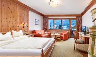 A cozy room with wood paneling and large windows that offer a beautiful view. It is equipped with a double bed, a living area, and modern amenities.