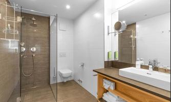 A modern bathroom with a rain shower and bright tiles. Personal care products and fresh towels are ready at the sink.
