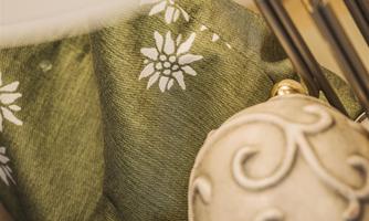 A decorative heart made of stone lies next to a green fabric with a floral pattern. In the background, some decorative sticks are visible.