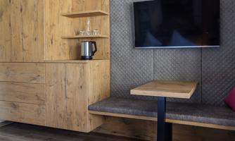 A modernly designed room with wooden shelves and a cozy seating area. A TV and a kettle are also available.