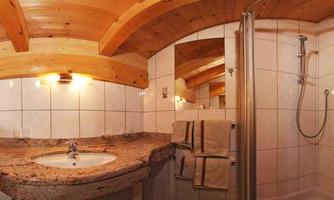 A modern bathroom with a wooden ceiling and a marble sink. The shower is freestanding and neatly arranged.