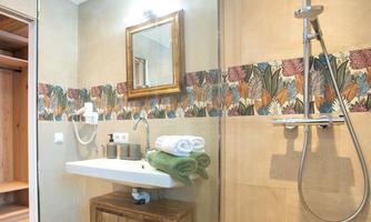A modern bathroom with an elegant shower and a large mirror. The walls are decorated with a colorful tile design and wooden details.
