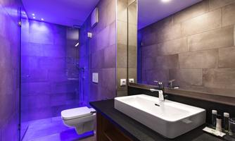 A modern bathroom with minimalist furnishings and an elegant sink. The soft blue lighting creates a relaxing atmosphere.