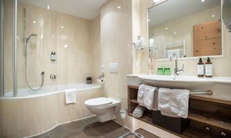 A modern bathroom with a shower and a bathtub. The walls are bright and the fixtures are clean and well-organized.
