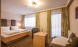 A cozy room with a double bed and a small table. Large windows provide plenty of daylight and a pleasant atmosphere.