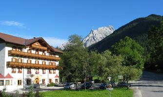 A charming hotel in a picturesque mountain landscape. The surroundings are green and surrounded by majestic mountains.