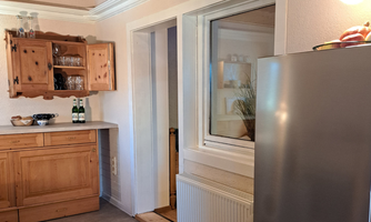 A cozy kitchen with wooden shelves and a refrigerator. A quiet room with neutral colors and a window.