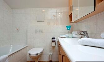 A modern bathroom with a bathtub and a toilet. Bright tiles and wooden cabinets create an inviting atmosphere.