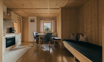 A cozy, wood-paneled apartment with a modern kitchen and dining area. Light streams through the windows, creating an inviting atmosphere.