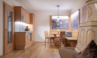 A cozy apartment with wooden decor and a modern kitchen. The dining area is inviting and offers a view of a mountain motif.
