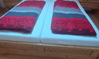 A cozy bedroom with a large bed and red, striped bedding. Next to the bed are two nightstands with lamps.
