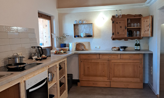 A cozy kitchen with wooden shelves and modern appliances. The room is bright and inviting, with fresh ingredients on the countertop.