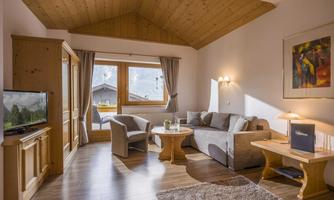 A cozy living room setup with a gray sofa and a round table. Large windows offer a view of the mountains.