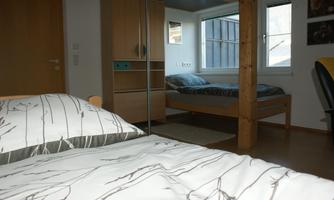 A cozy bedroom with two beds and a loft bed.