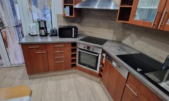 A modern kitchen with wooden cabinets and stainless steel appliances. It is well-lit and offers space for multiple kitchen utensils.