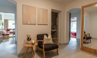 A cozy hallway with a modern armchair and a small table. Two decorative pictures hang on the wall, and a large mirror provides more light and space.