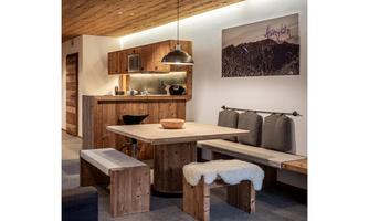 A cozy living kitchen with wooden paneling and a modern table. The decor exudes warmth and an inviting atmosphere.