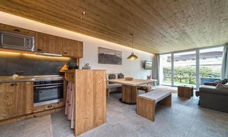 A modern kitchen with wooden cabinets and a large dining area. The open design provides plenty of light and a view of the garden.