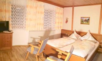 A comfortable hotel room with two beds and soft, warm colors. There is a television and a small table with chairs.