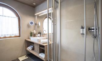 A modern bathroom with a shower and a wooden vanity. The light is friendly and the atmosphere is inviting.