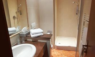 An elegant bathroom with a modern shower and a sink. Towels are neatly arranged and the walls are in neutral colors.