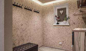 A small hallway with an upholstered bench and several hooks on the wall. On the windowsill, there is a plant and a decorative figure.