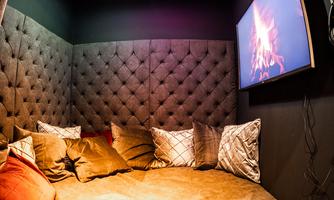 A cozy retreat with a round bed, soft pillows, and a television that shows a campfire. The room has a atmospheric ceiling with sparkling lights.