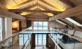 A modern, open living space with a wooden ceiling and large windows. The bright interior creates an inviting atmosphere.