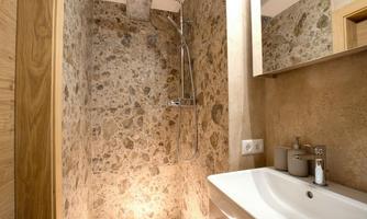 A modern bathroom with a natural stone shower. The sink is elegant, and there is plenty of natural light.