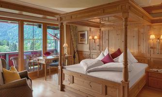 A cozy bedroom with a wooden four-poster bed and a view of the mountains. The room is tastefully decorated and offers an inviting atmosphere.