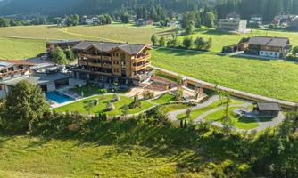 A modern hotel situated in a green landscape. The property features a pool and well-maintained outdoor areas.