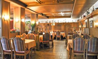 An inviting restaurant with wooden furniture and a cozy atmosphere. The tables are nicely set, and there are plants for decoration.