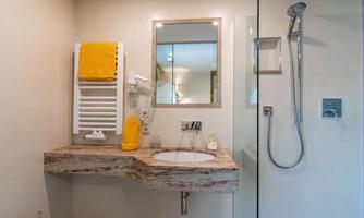 A modern bathroom with a bright sink countertop and a shower. Yellow towels and decor add a fresh touch to the space.