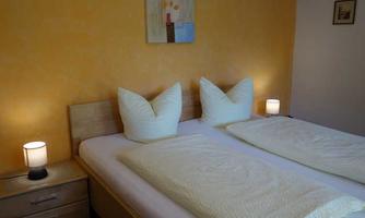A cozy bedroom with a double bed and yellow walls. Lamps on the nightstands create a warm atmosphere.