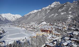 A picturesque winter scene with snow-covered mountains and a charming village. The landscape is clear and sunny, perfect for winter activities.