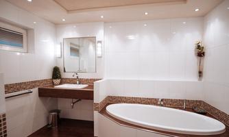 A modern bathroom with a freestanding bathtub and an elegant sink. The walls are tiled in light colors, and there are stylish lighting elements.