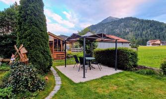 Home garden with a pavilion and a table with chairs. Mountains can be seen in the background.