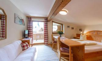 A cozy room with wooden paneling, a fitted kitchen, and a dining area. Large windows provide plenty of daylight and a beautiful view outside.