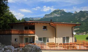A modern house with a large terrace and mountain view. Surrounded by trees and natural scenery.