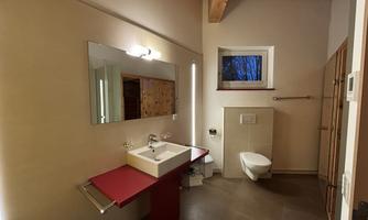 A modern bathroom with a red sink countertop and a large mirror. The lighting creates a bright and inviting atmosphere.