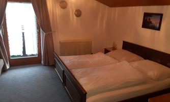 A cozy bedroom with a double bed and two pillows. The window lets in plenty of light and the room has a rustic charm.